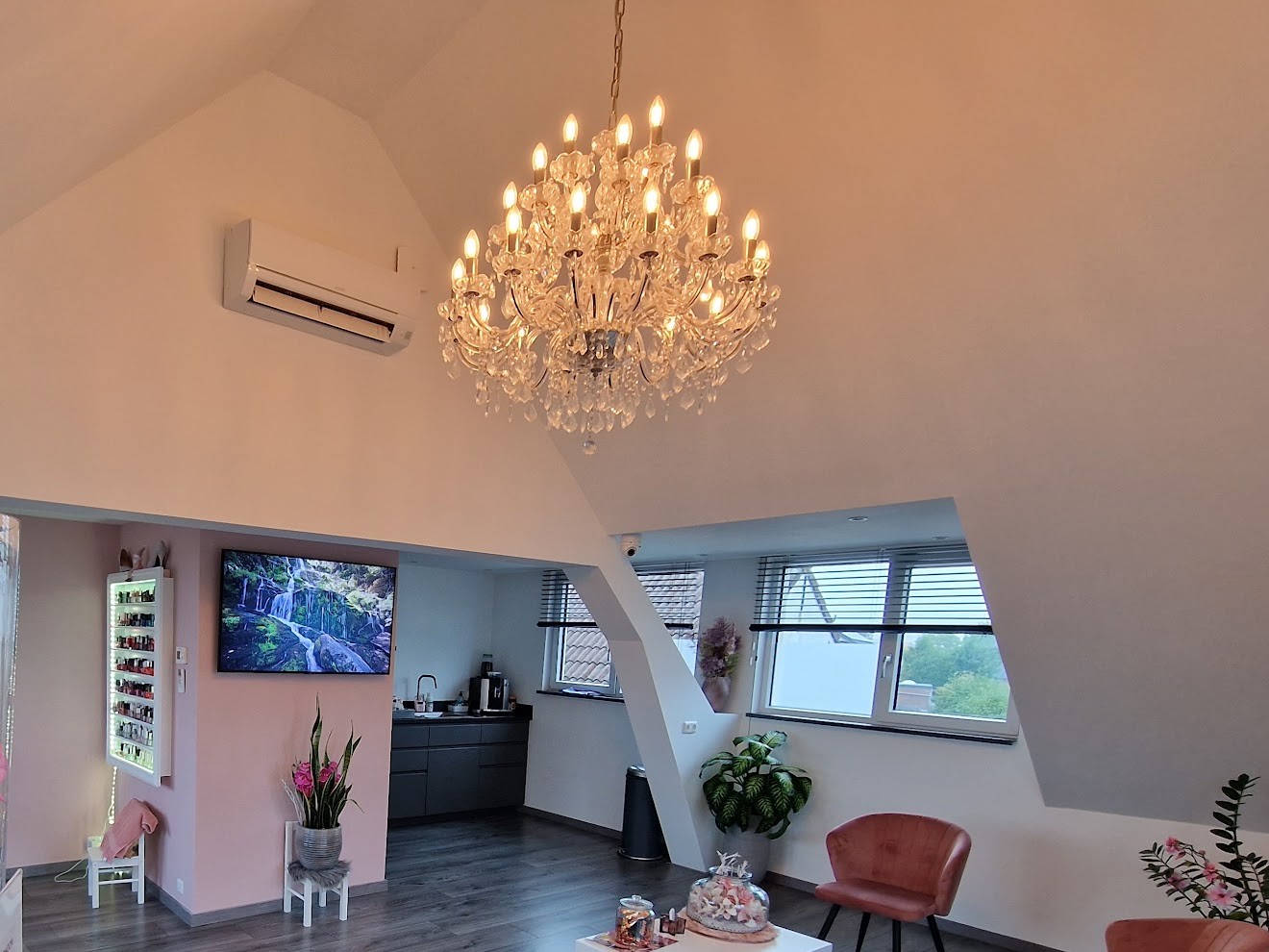 De roze studio van Katia's Beauty Studio onder het dak, met kroonluchter, nagellakwand en stoelen